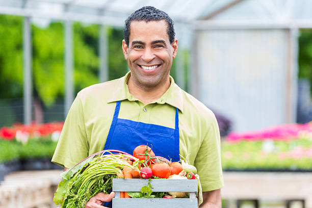 a smiling man presenting his vegetables for sale